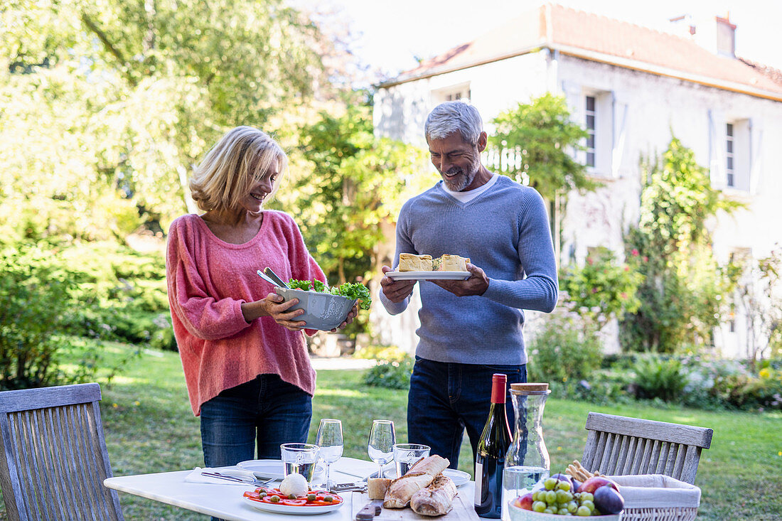 Älteres Paar serviert das Essen am Tisch im Freien