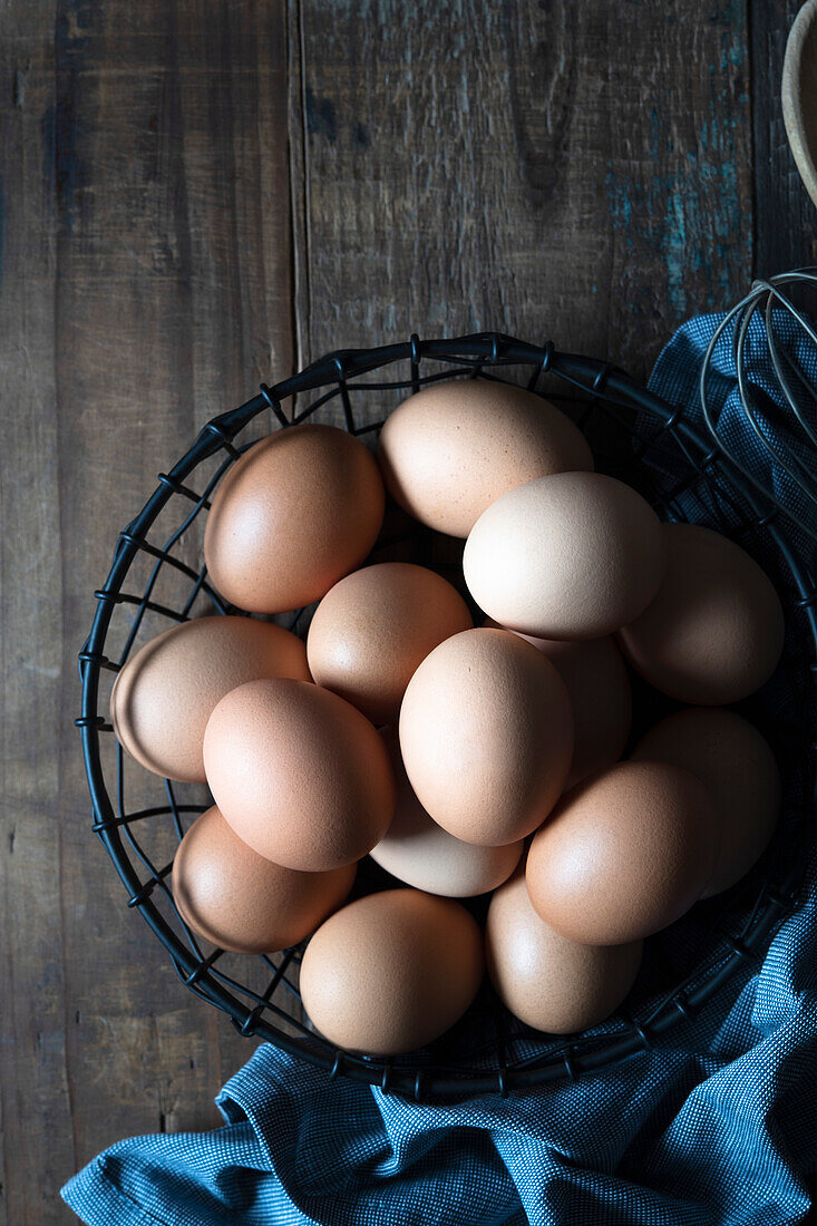 Eggs in a wire basket on a wooden background
