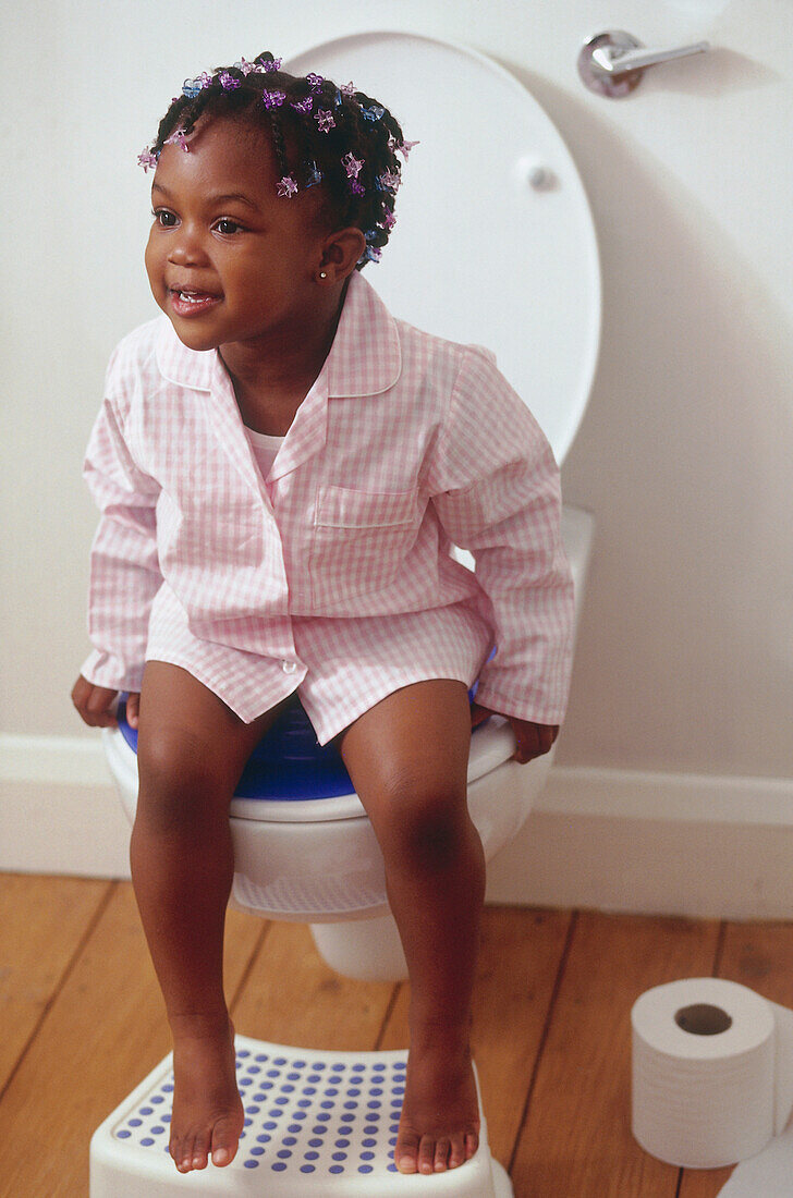 Young girl sitting on toilet