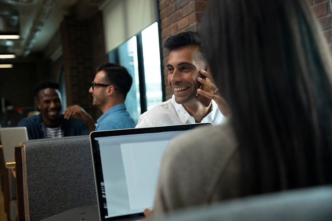 Happy businessman talking on smart phone in meeting