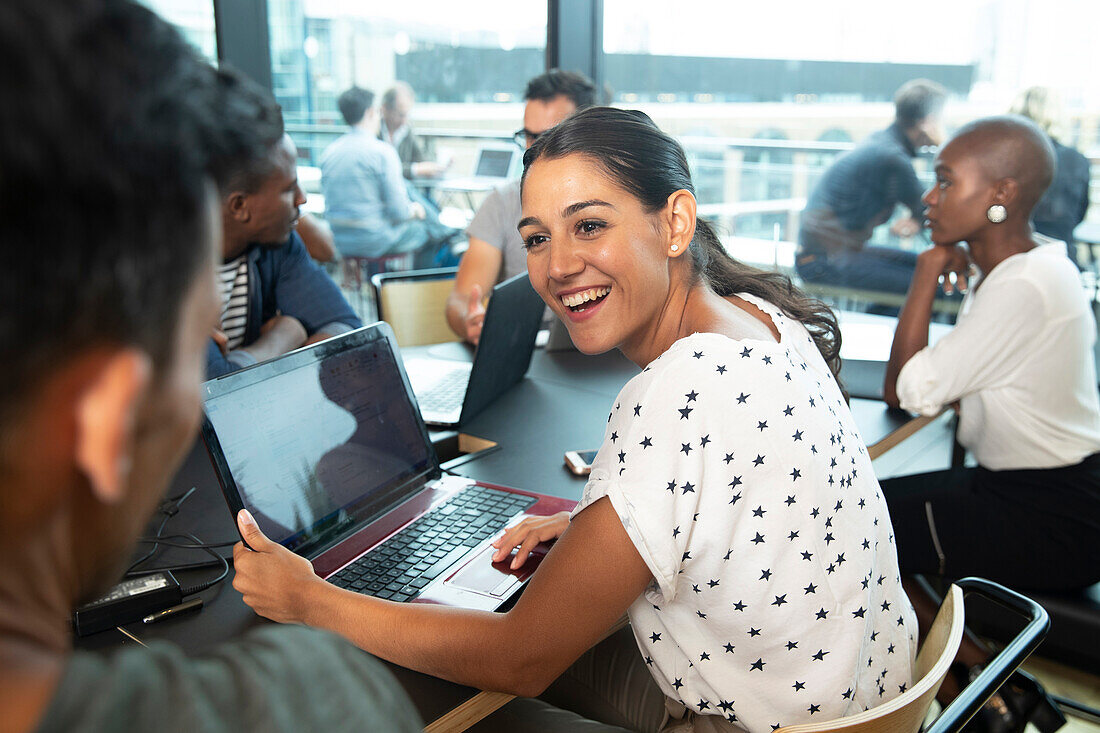 Businesswoman with laptop talking to colleague in office