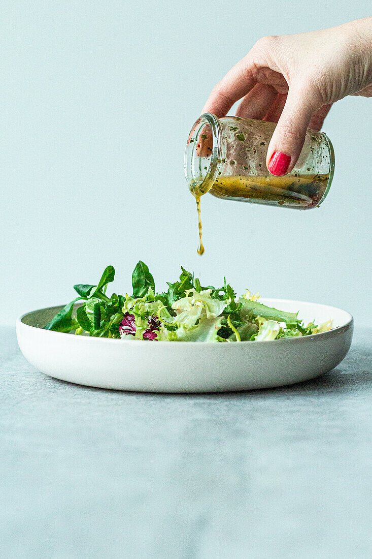 Italian dressing being poured over a salad