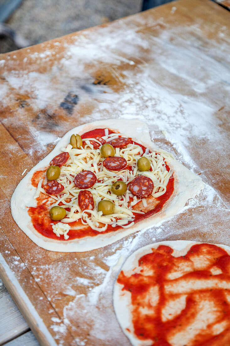 Raw pizza with pepperoni and olives