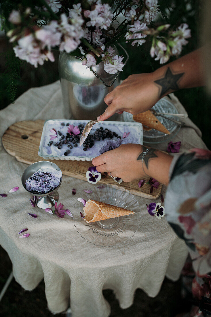 Frauenhände halten Teller mit Blaubeereis