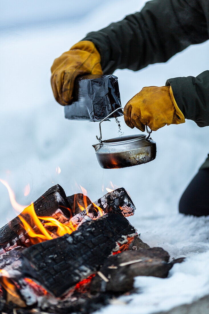 Person making coffee over campfire