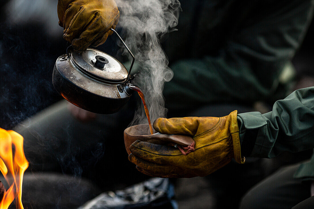 Hands pouring hot coffee from kettle
