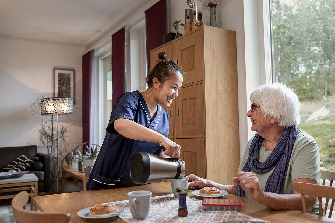 Home carer preparing coffee break for senior woman