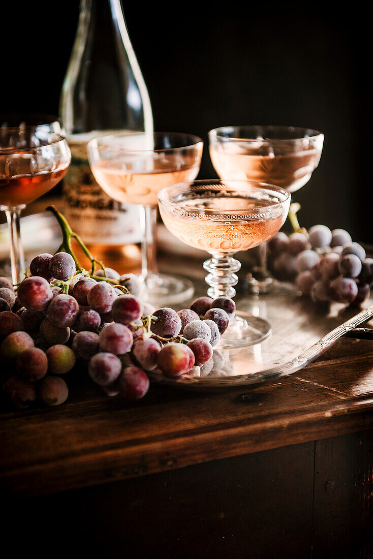 Roséwein in Gläsern und gefrorene Trauben auf Tablett