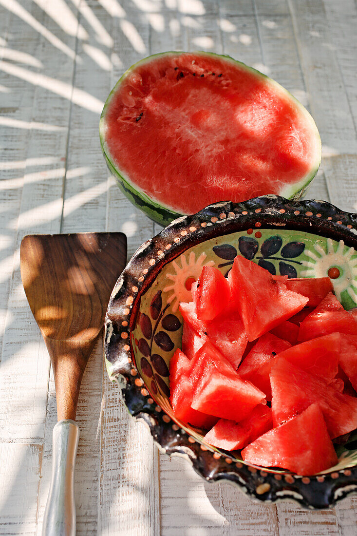 Halbierte Wassermelone und Melonenstücke in Keramikschale