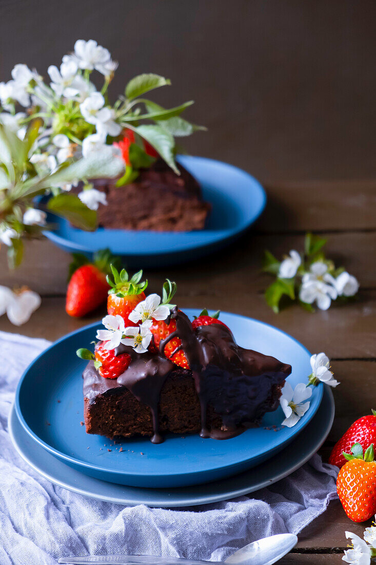 Ein Stück Brownie mit Schokoladensauce und Erdbeeren