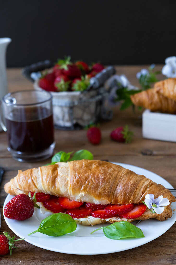 Butter croissant with strawberries and basil leaves
