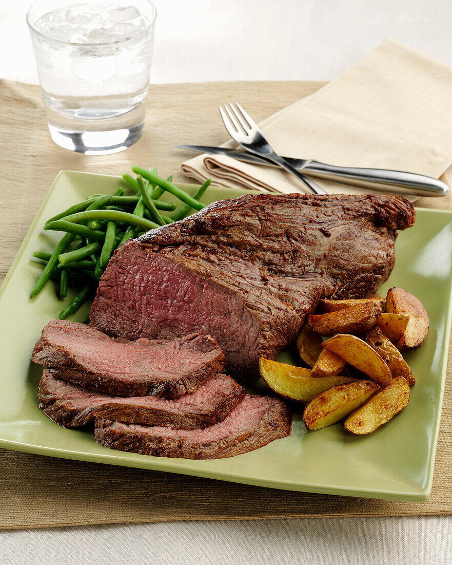 A beef Tri Tip roast with roasted potato wedges and green beans