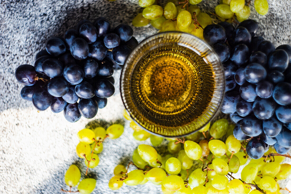 Georgischer trockener Weißwein im Glas daneben frische Trauben
