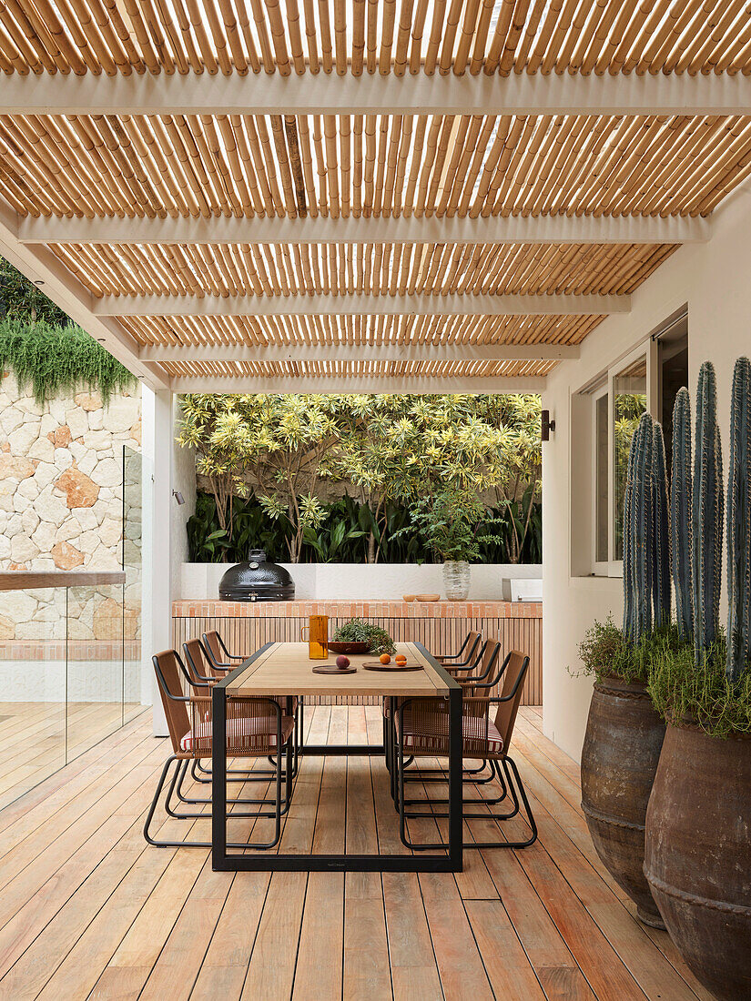 Dining table with chairs and cacti on covered terrace