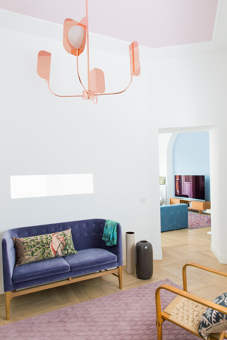 Purple upholstered sofa and designer lamp in a bright, renovated old flat