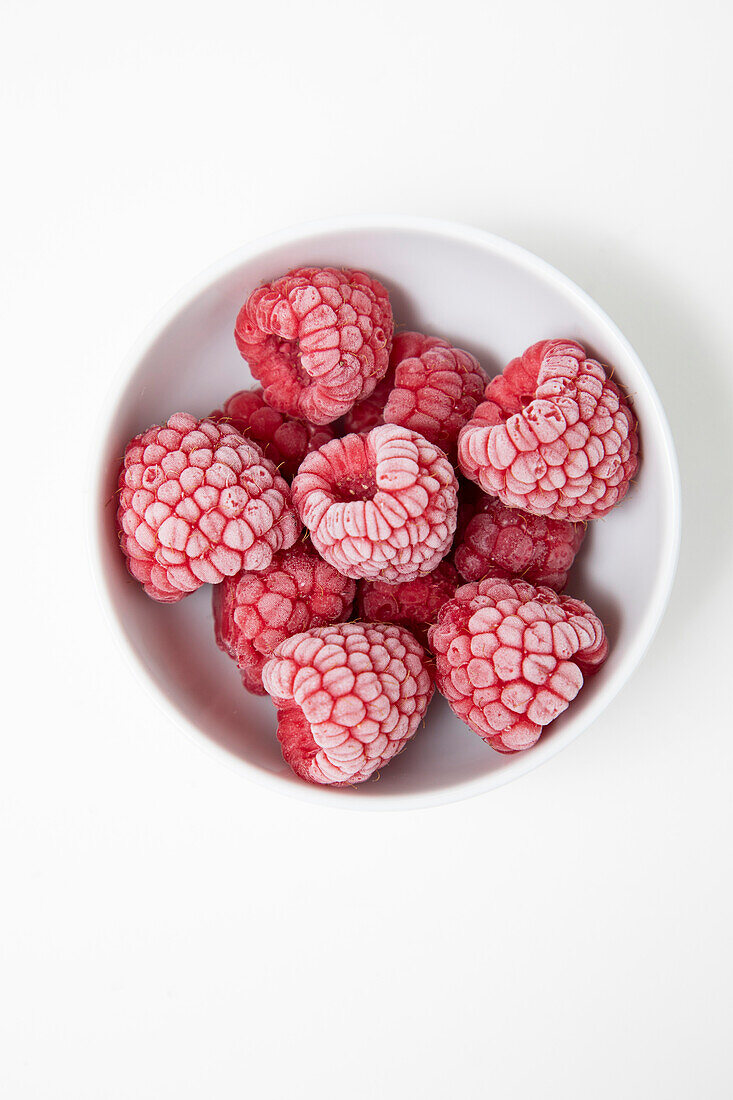 Frozen Raspberries in a white bowl on a white background