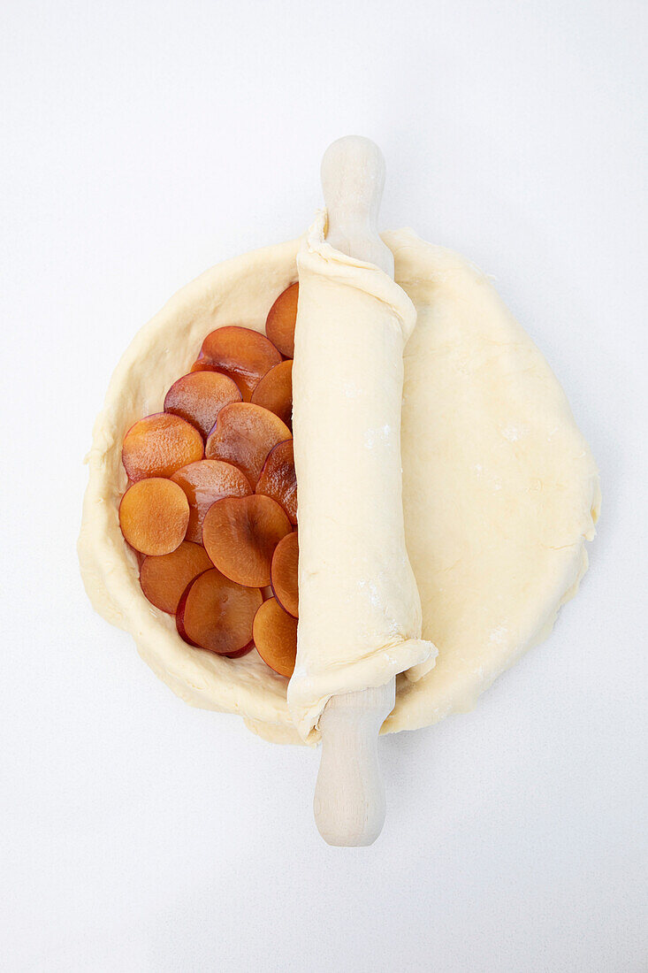 Pflaumenkuchen zubereiten: Kuchendeckel darüber rollen