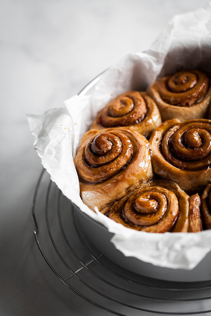 Cinnamon buns in a round pan with parchment paper.