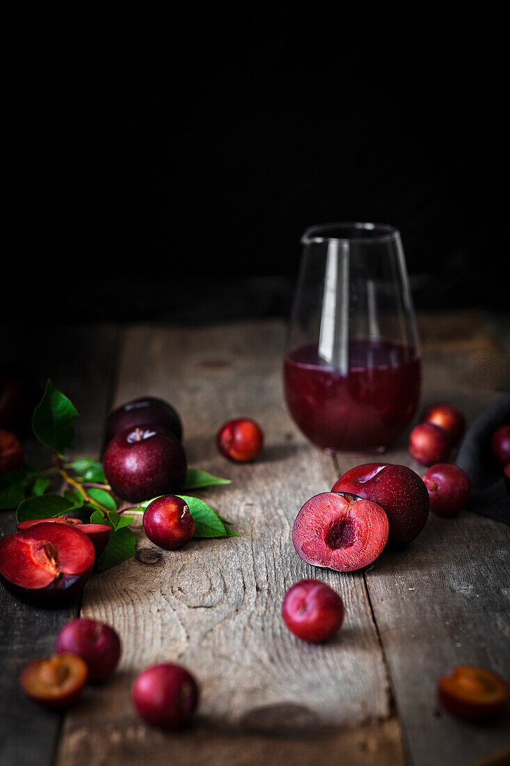 A glass of plum juice and fresh plums