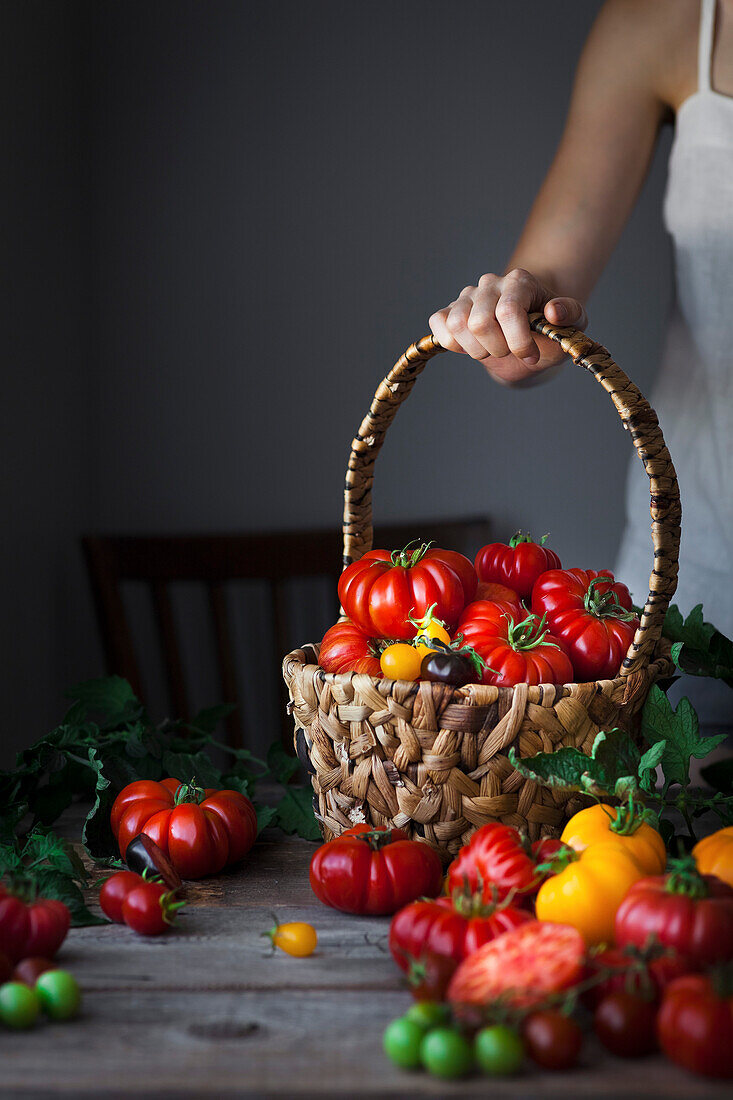 A person holding a basket of heirloom tomatoes