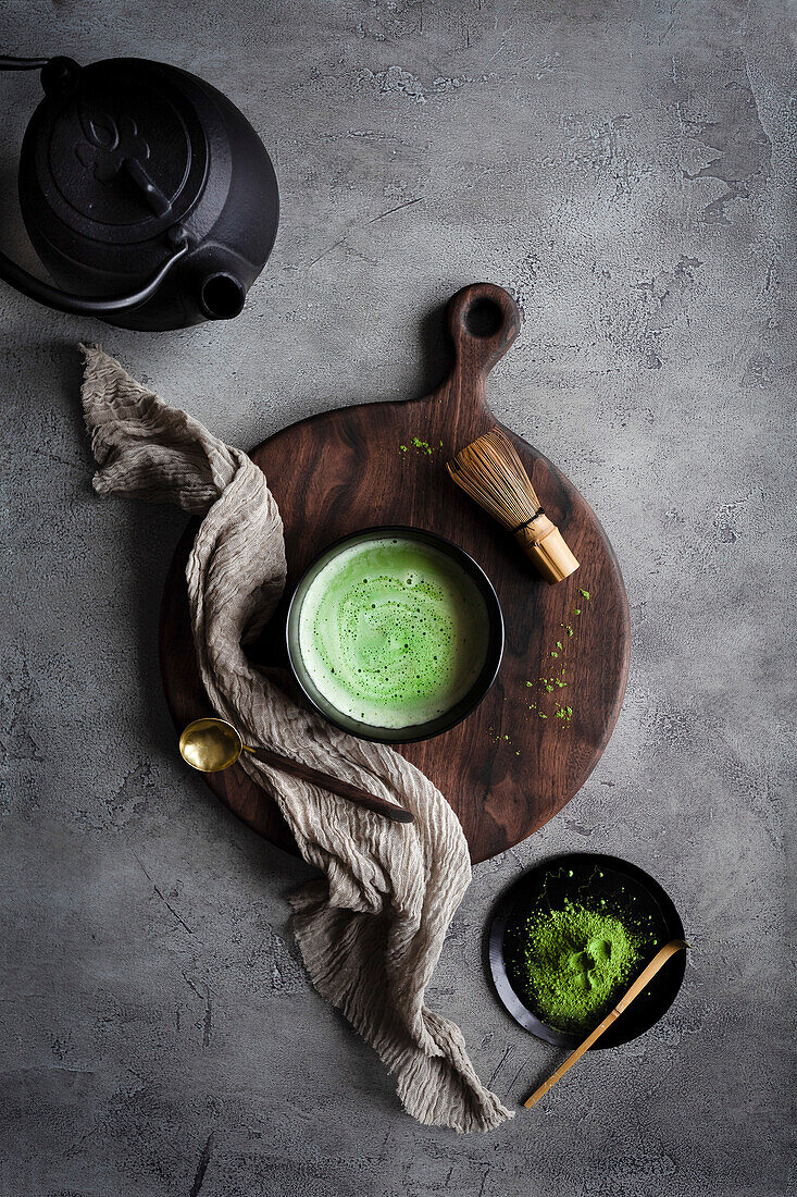 Matcha tea with a kettle and whisk on a dark surface