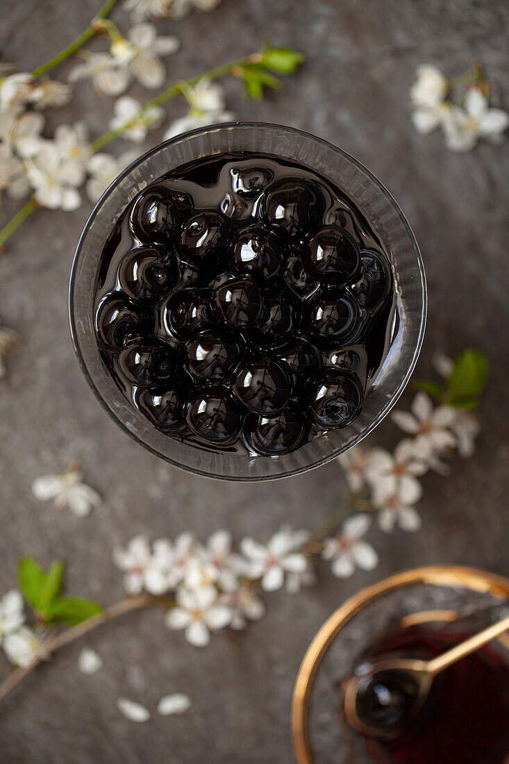 A bowl of dark coloured maraschino cocktail cherries in syrup