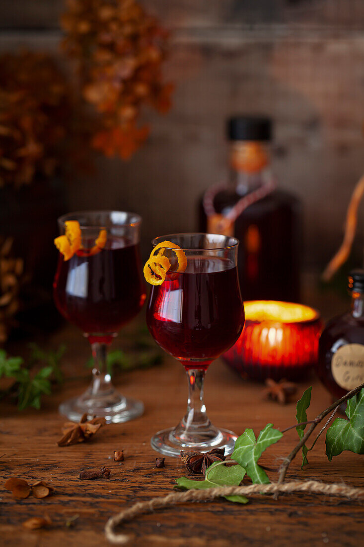 Glasses of damson gin liqueur served in sherry glasses with a twist of orange zest.