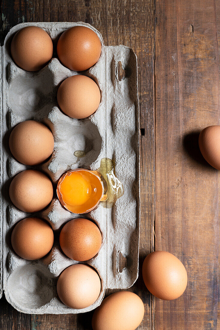 Hühnereier im Eierkarton, ein Ei gebrochen