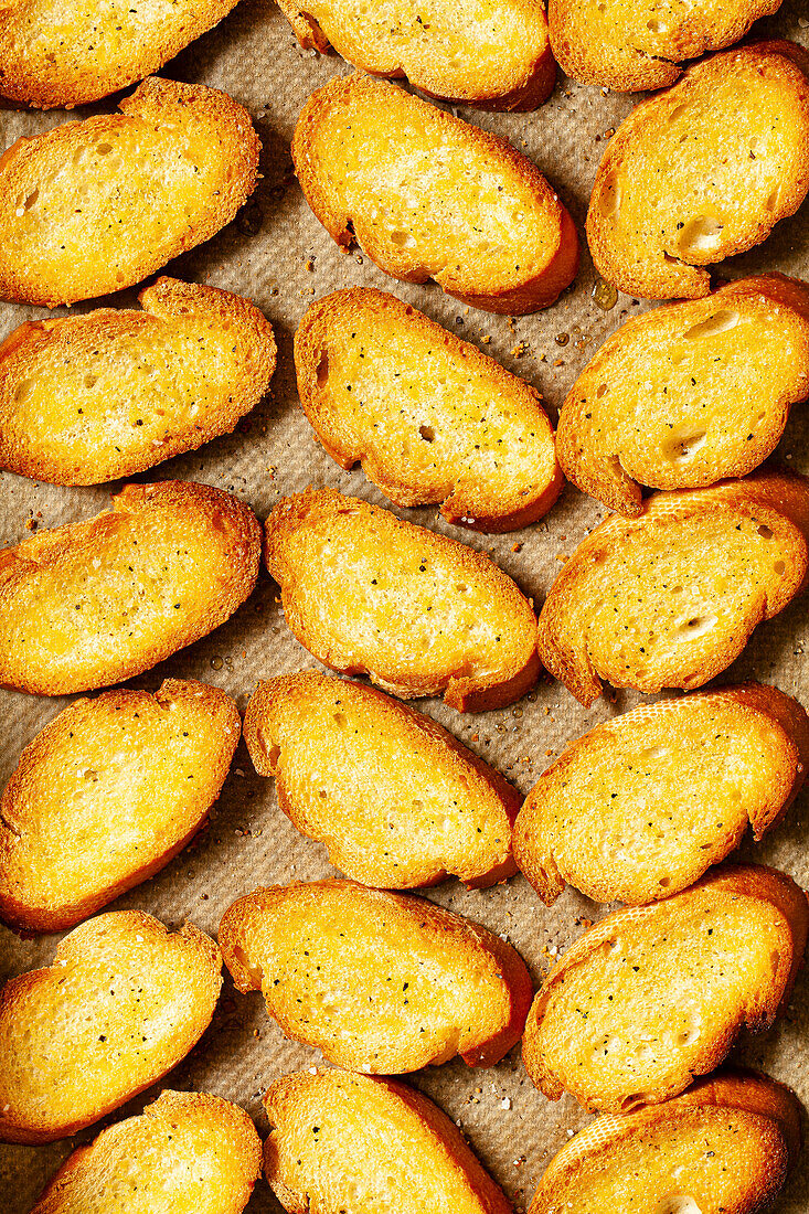 Slices of freshly baked crostini bread on baking parchment