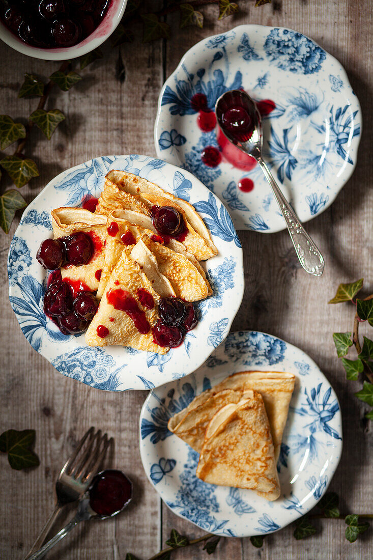 English style pancakes folded onto plates and served with cherry sauce
