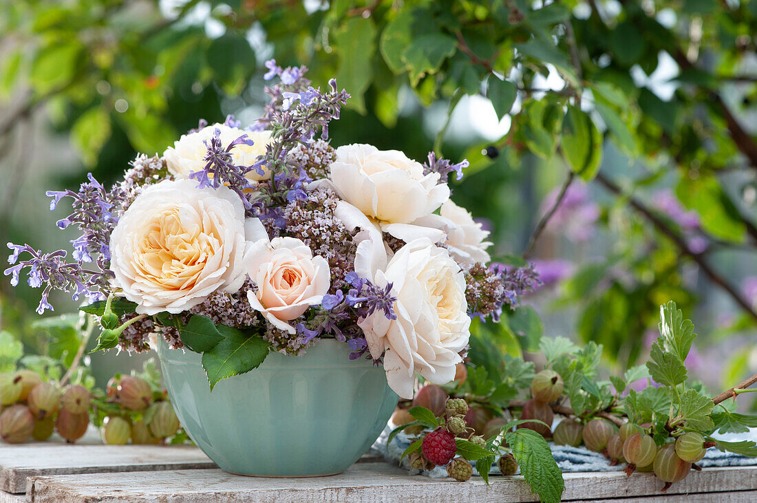 Summer arrangement of roses, catnip, and oregano flowers, branches with gooseberries and raspberries