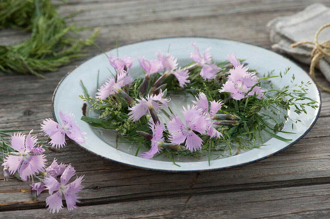 Grass wreath with cloves floats in bowl with water