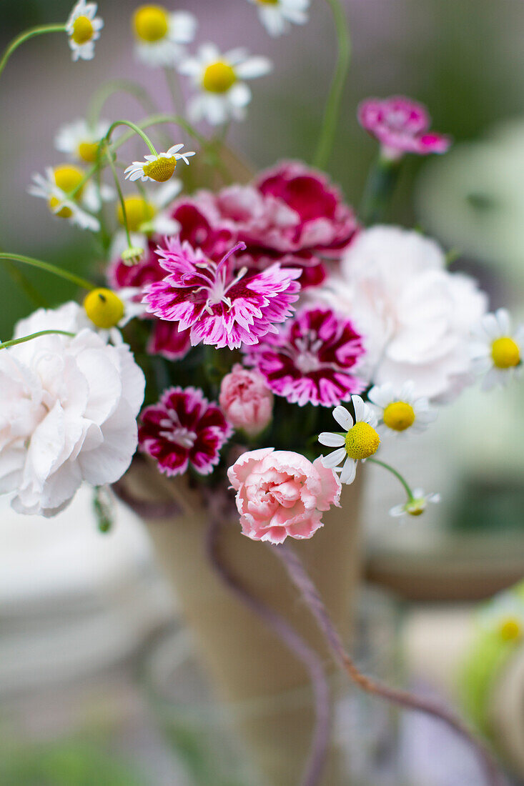 Small scented bouquet of carnation blossoms and camomile in a homemade paper bag