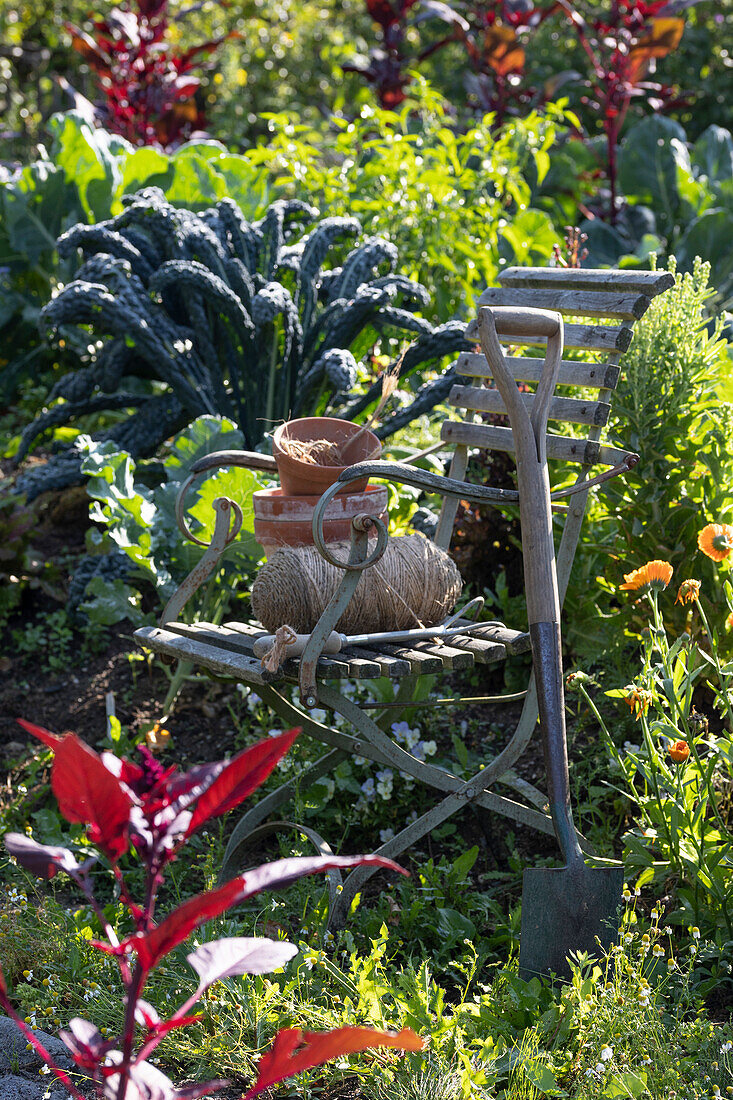 Garden chair in a cottage garden between vegetables and perennials