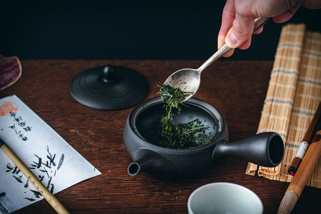 Japanischer grüner Tee - lose Blätter werden in Kanne gegeben