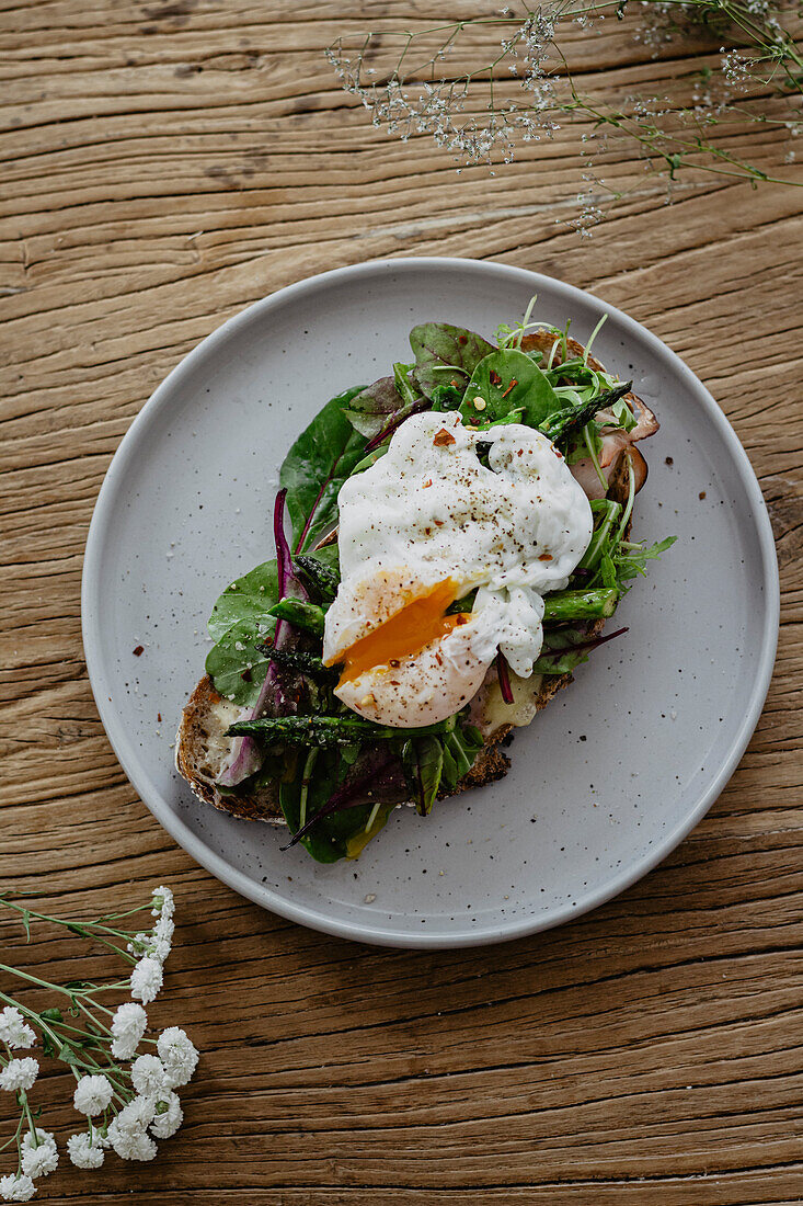 Toast with asparagus, poached egg, greens and ham