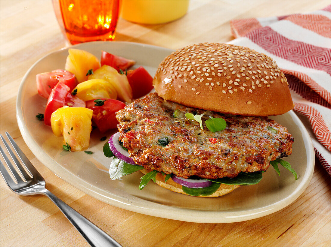 Ground chicken and roasted vegetable burger with salad greens and onions