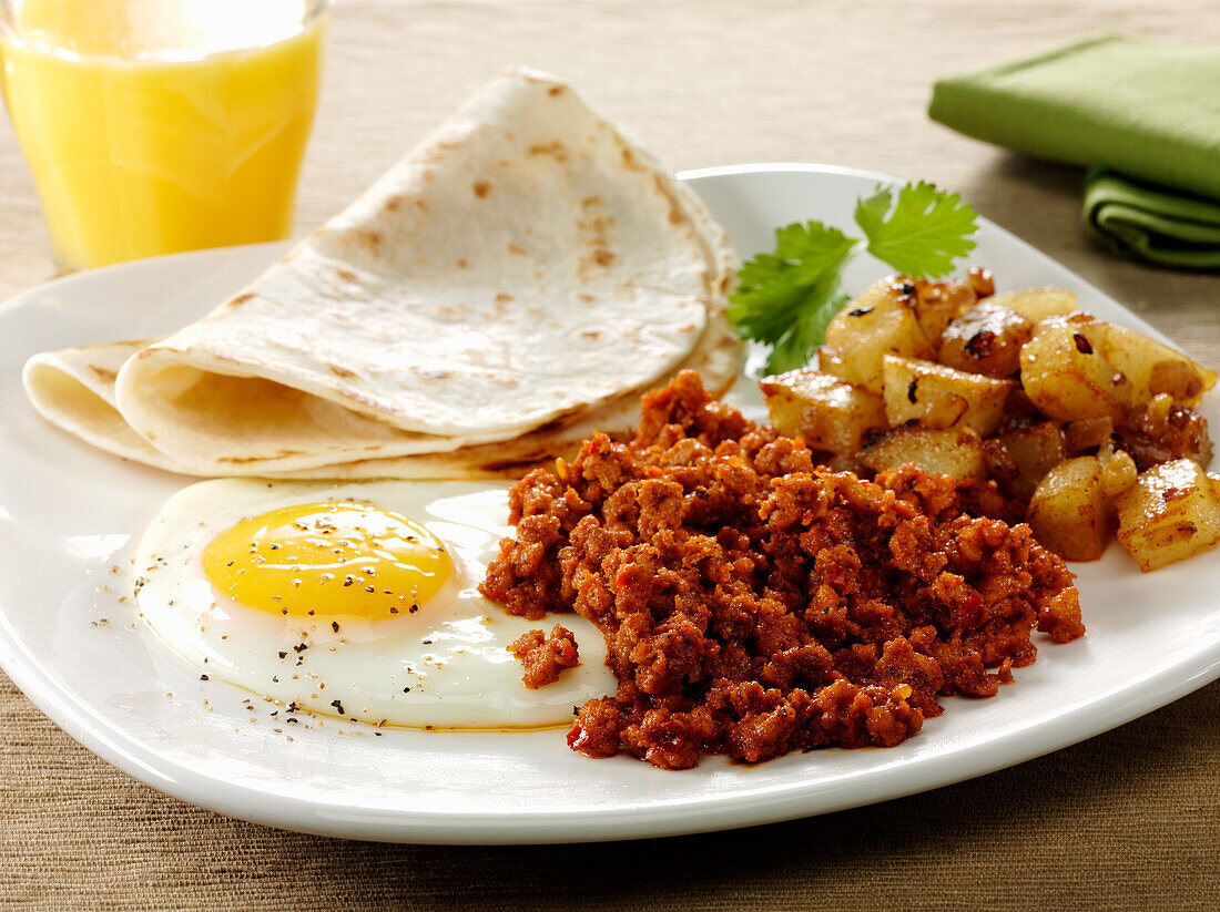 Mexican style Chorizo and fried egg breakfast with tortillas and hash browned potatoes