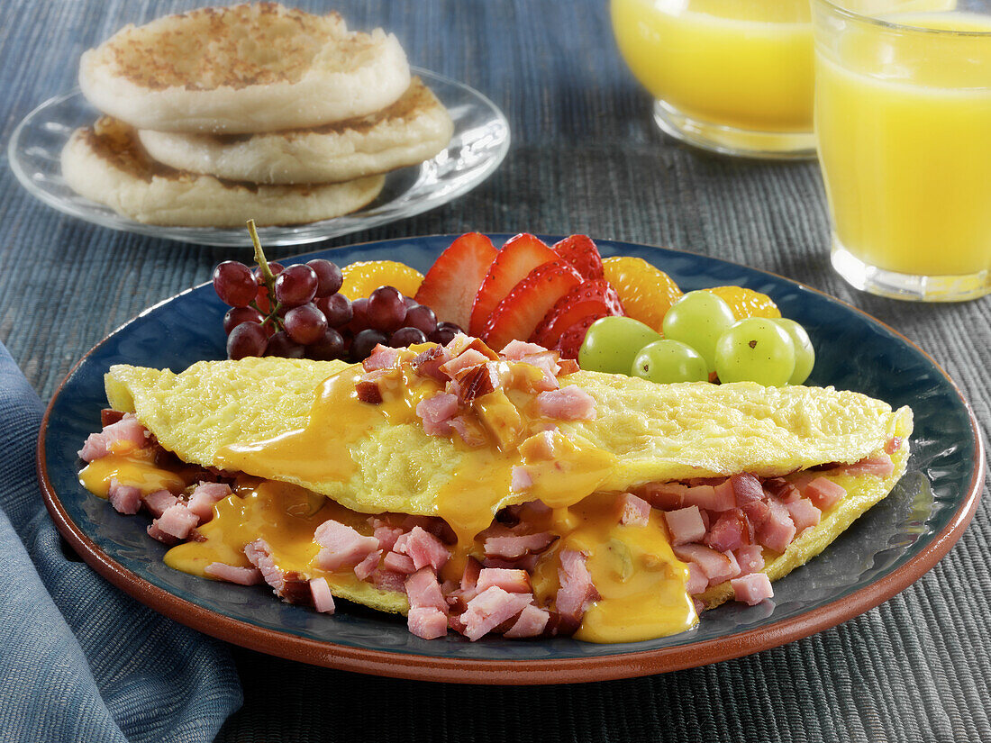 Ham and cheese omelette with fruits with English muffins and orange juice