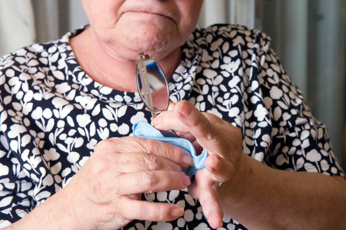 Elderly woman cleaning a pair of spectacles