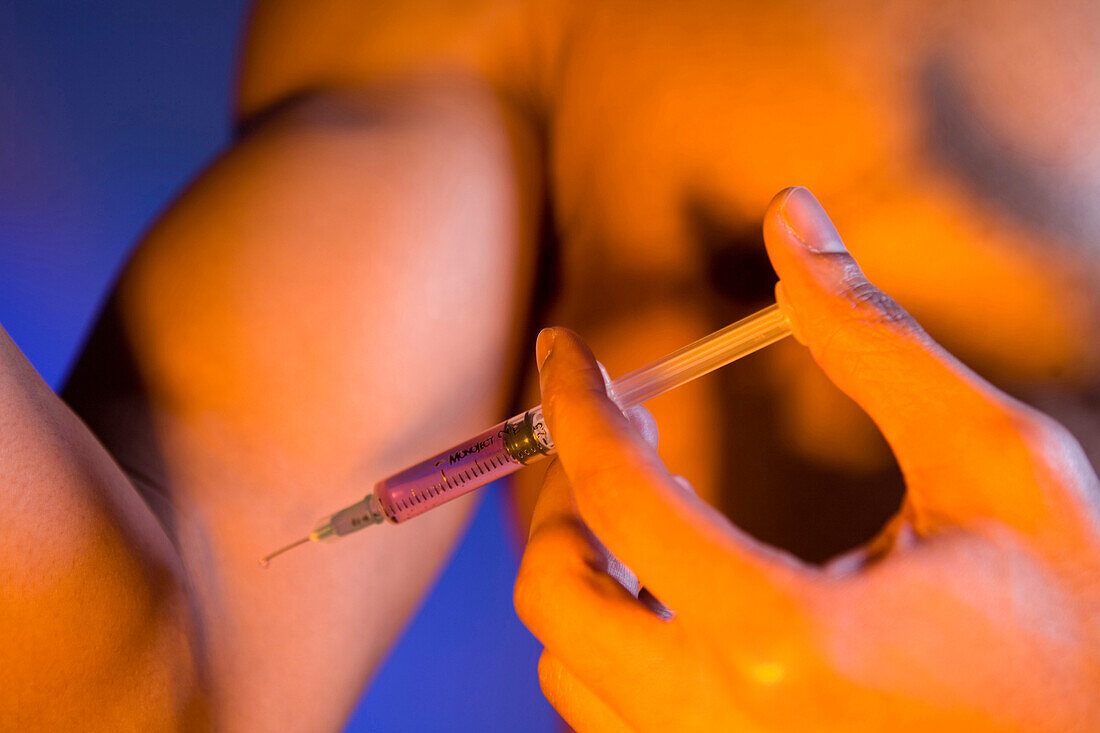 Young man injecting anabolic steroids