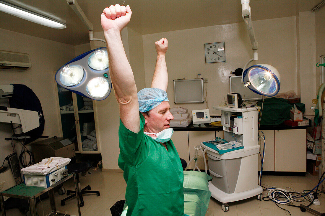 Tired overworked surgeon stretches his arms