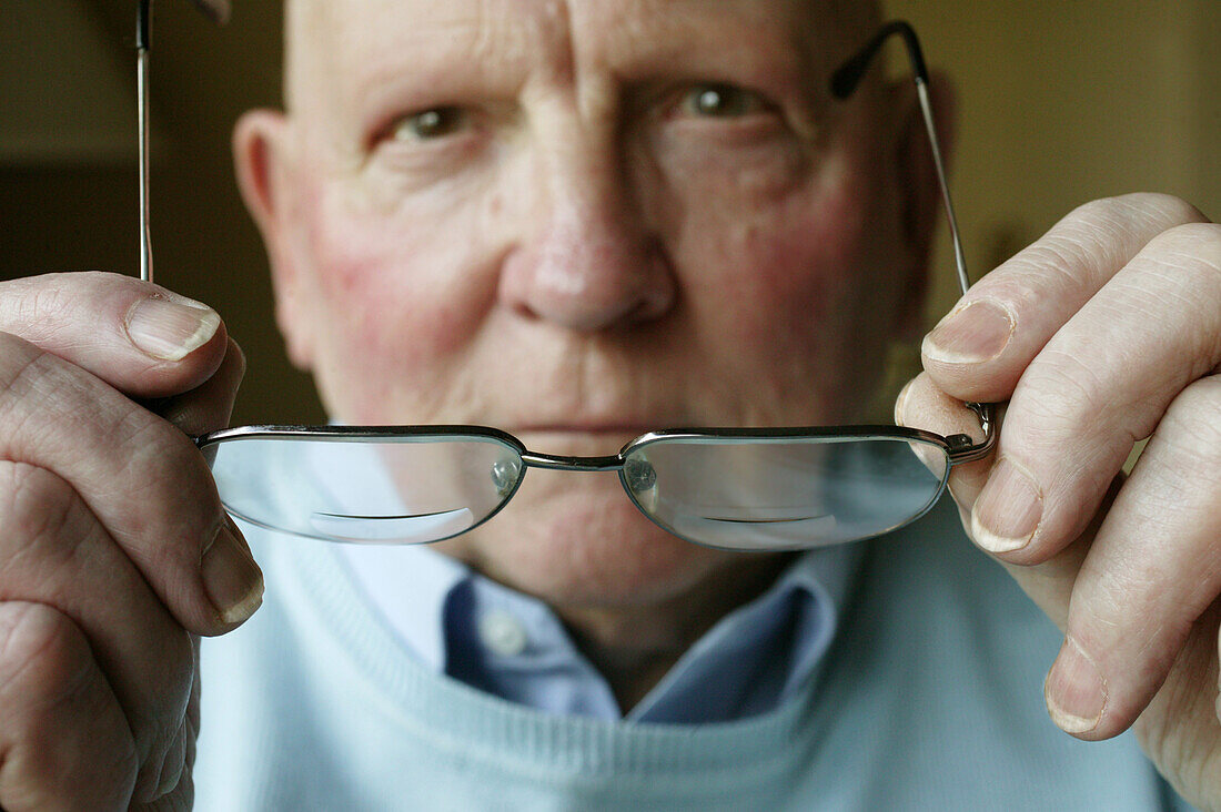 Elderly man putting on his glasses