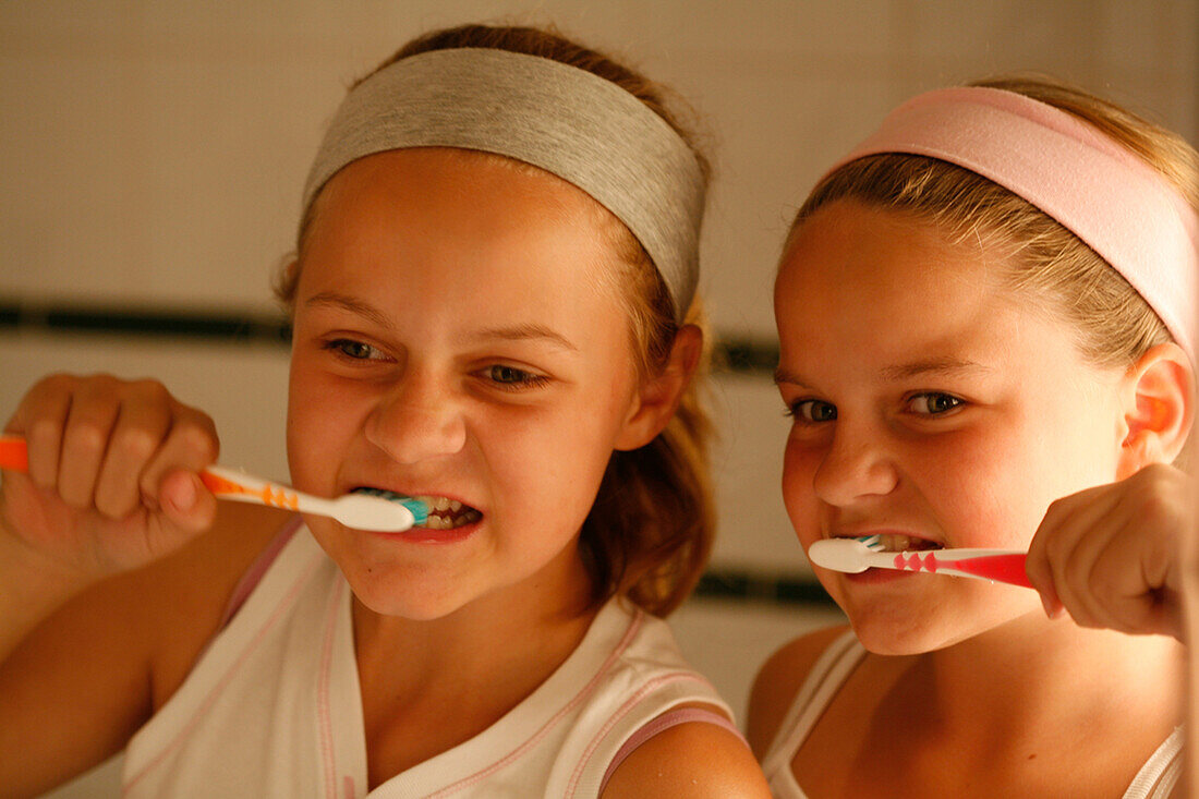 Two girls brushing their teeth