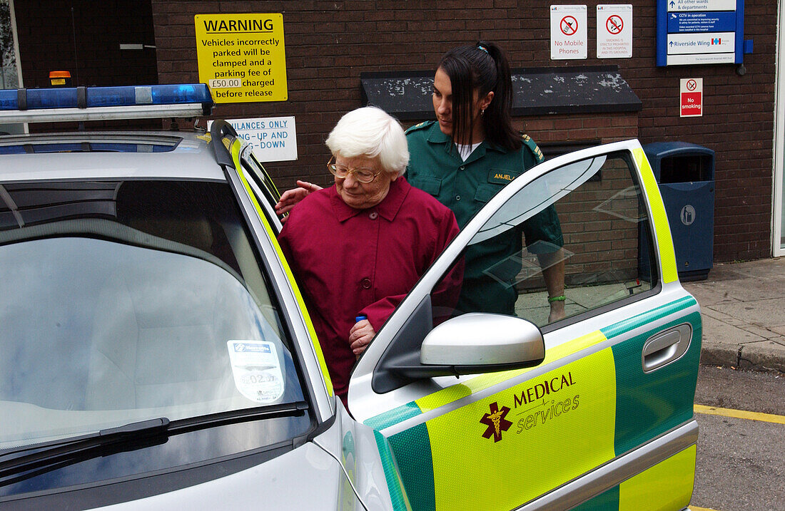 Emergency medical technician escorting an elderly woman into an