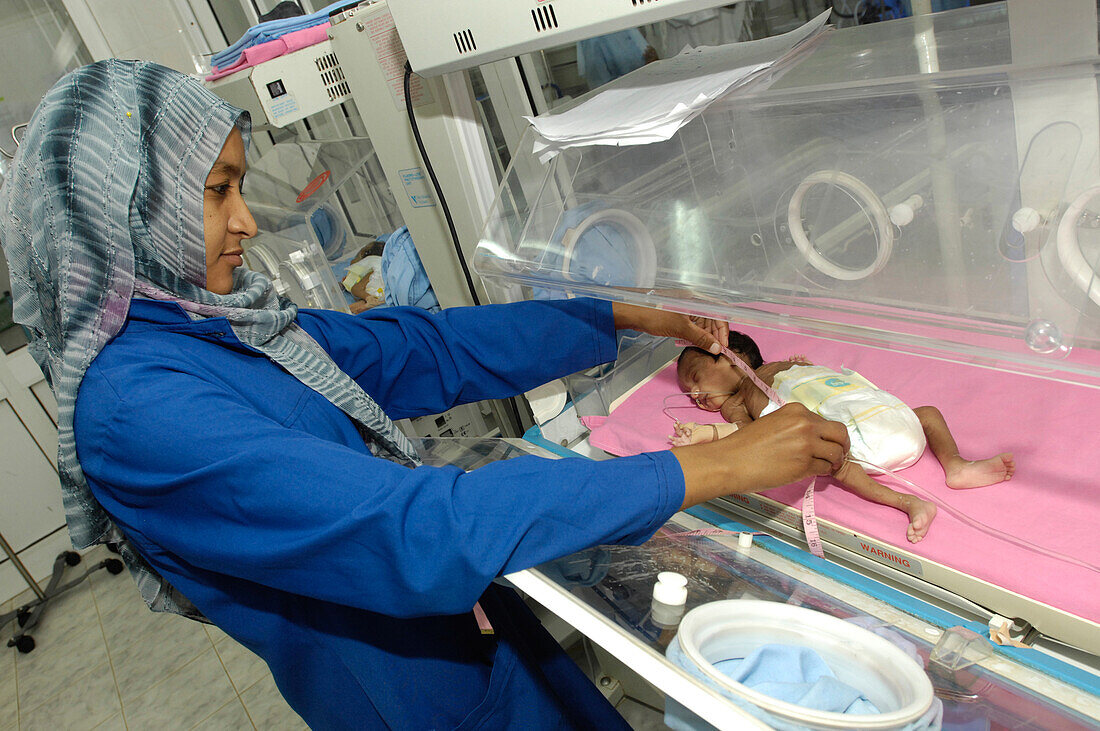 Neonatal nurse examining a premature baby