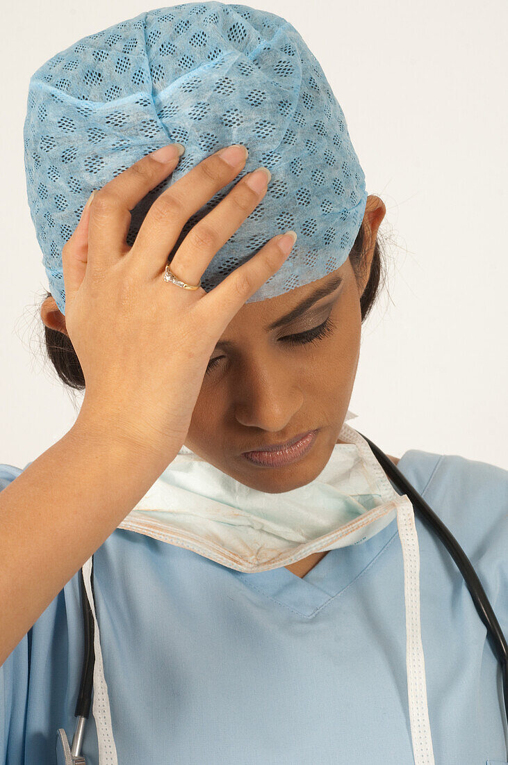Overworked surgeon holding her head