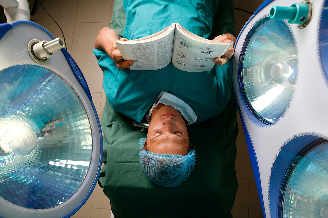 Surgeon laying on an operating table whilst reading a book