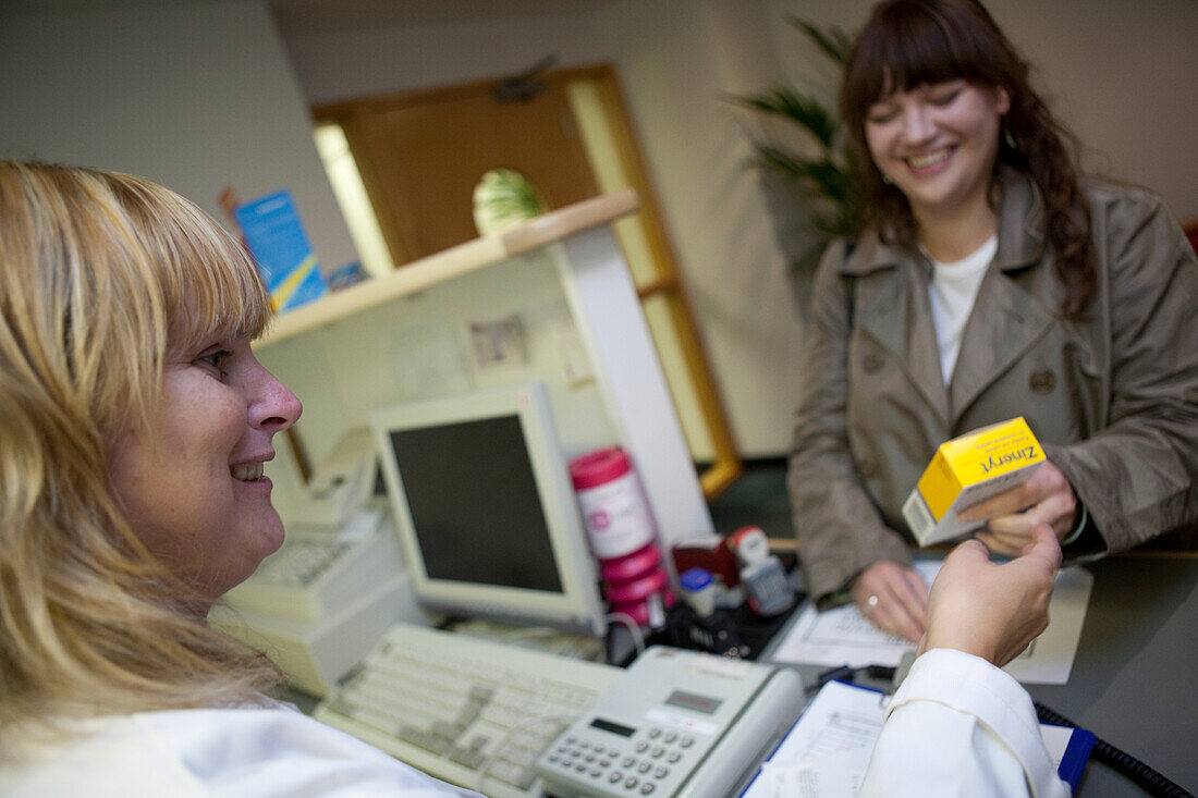 Pharmacy technician handing a prescription drug to a patient