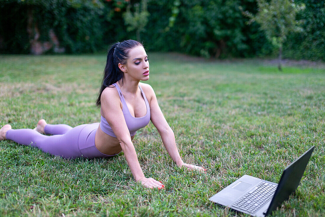 Young woman stretching body and watching tutorial video